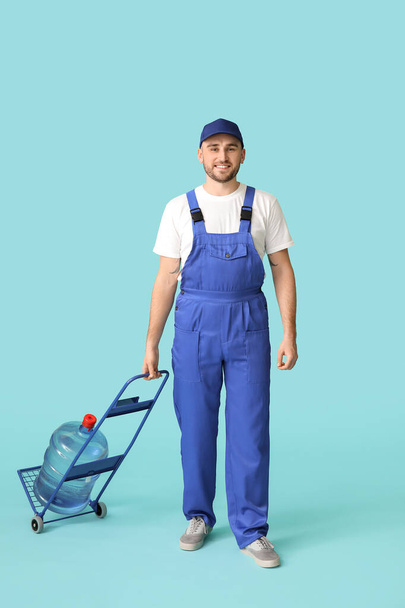 Delivery man with bottle of water on color background - Φωτογραφία, εικόνα