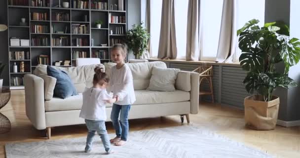 Two happy children girls holding hands dancing in living room - Filmati, video