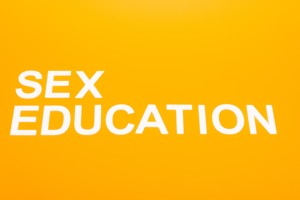 bovenaanzicht van seksonderwijs belettering geïsoleerd op oranje  - Foto, afbeelding