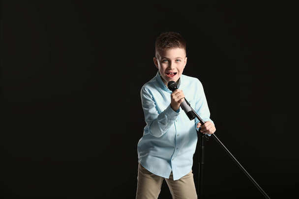 Cute little boy singing against dark background - Photo, Image