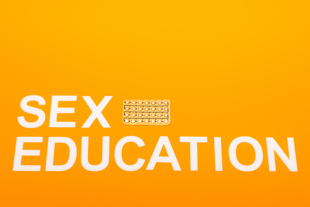 vista superior da educação sexual lettering perto blister pack com pílulas contraceptivas isoladas em laranja
  - Foto, Imagem