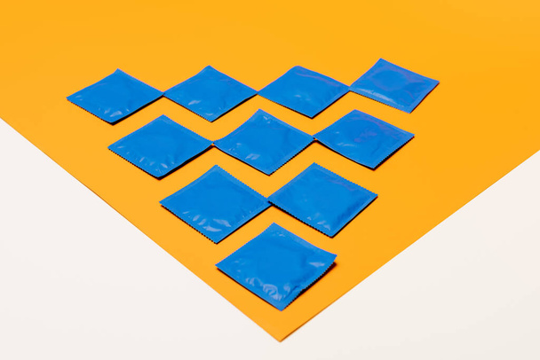 verpakkingen met condooms op oranje oppervlak geïsoleerd op wit - Foto, afbeelding