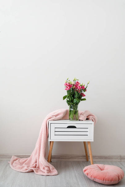 Стол с теплым пледом, букет цветов и подушка в номере
 - Фото, изображение