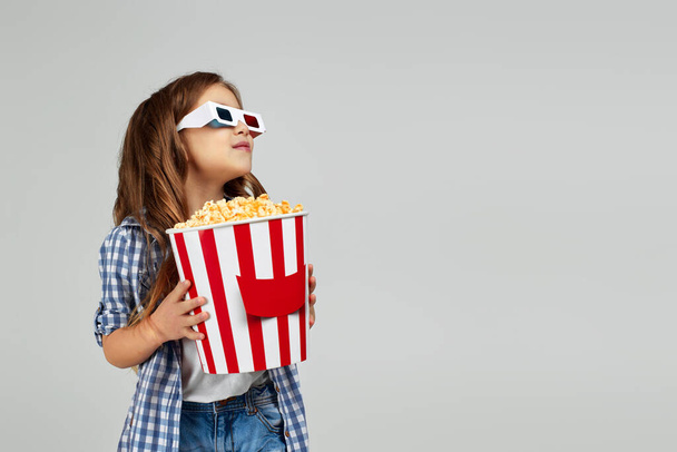 kind meisje dragen rood-blauwe 3d bril en het eten van popcorn - Foto, afbeelding