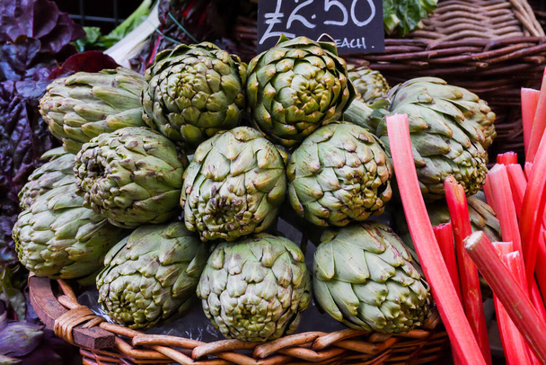Green and red artichoke.Local produce for sale displayed at the market. Borough farmer's market in London. Organic and bio fresh healthy eating concept.Veggies, vegetables, herbs and spices,price tags - 写真・画像