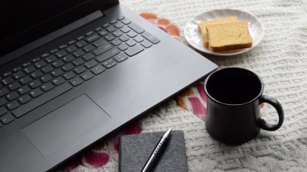 Ontbijt koffie in de ochtend zonlicht met laptop computer zwarte kleur pen en persoonlijke organisator notebook, keramische kop schotel en biscuit op top kantoor plaats werkbureau achtergrond. Lifestyle imago. - Video