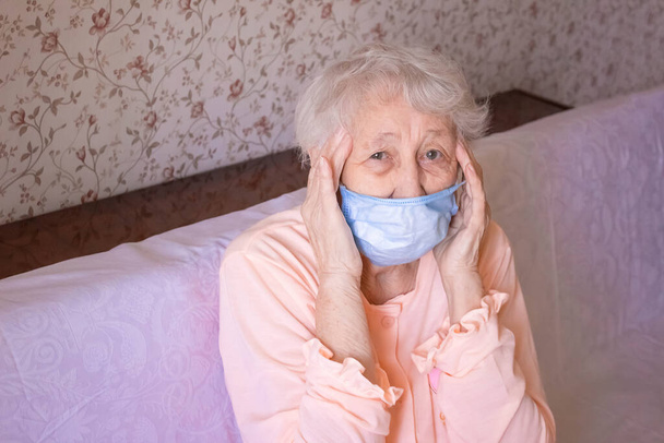 Koronawirus, Covid-19, koncepcja zdrowia, bezpieczeństwa i pandemii, opieka, ból, stres, wiek i koncepcja ludzi - twarz starszej kobiety cierpiącej na ból głowy w domu - Zdjęcie, obraz