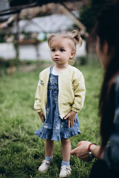 03.06.2018 Vinnitsa, Ukraine: lportrait of a cute little girl playing in the cold weather in the backyard of the house - Fotó, kép