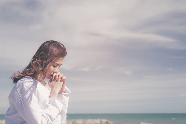 Woman praying with hands together with sea background. - Foto, Imagen