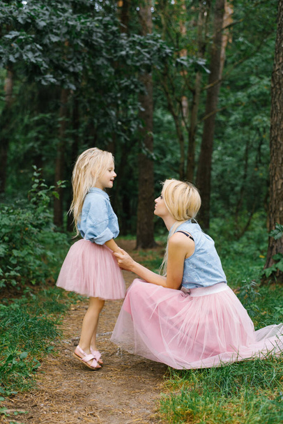 Matka i pięcioletnia córka w tych samych romantycznych ciuchach spacerują po parku lub w lesie, rozmawiają i rozmawiają o czymś. Dzień Matki - Zdjęcie, obraz
