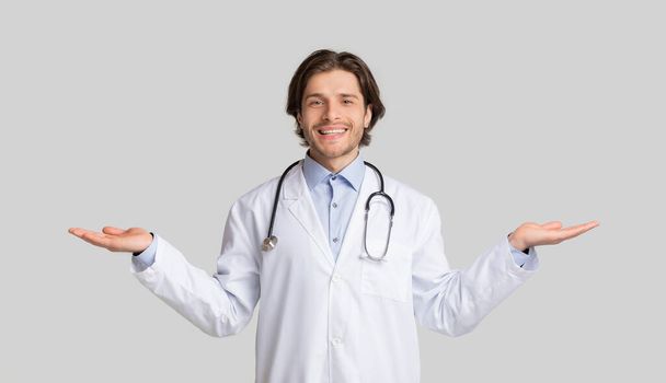 Přátelský mužský lékař demonstrující neviditelné objekty na otevřených dlaních - Fotografie, Obrázek