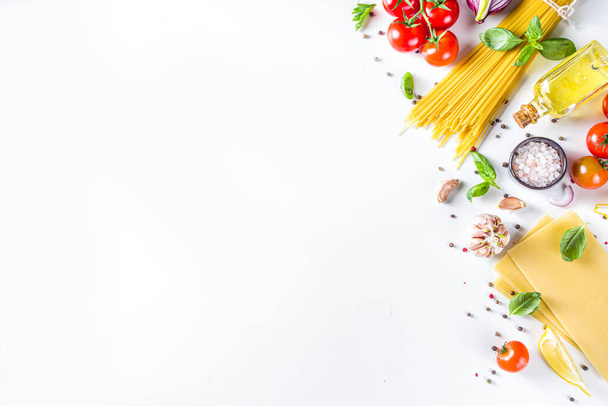 スパゲティパスタを調理するためのイタリア料理の成分。タマネギ、トマト、ニンニク、バジル、パセリ、チーズ、オリーブオイル。白いテーブルの背景には、フラットレイコピースペース - 写真・画像