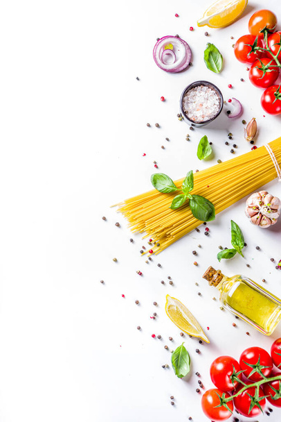 Italian food ingredients for  cooking Spaghetti Pasta. Raw spaghetti pasta with various ingredient - onion, tomatoes, garlic, basil, parsley, cheese, olive oil. On white table background, flatlay copy space - Photo, Image