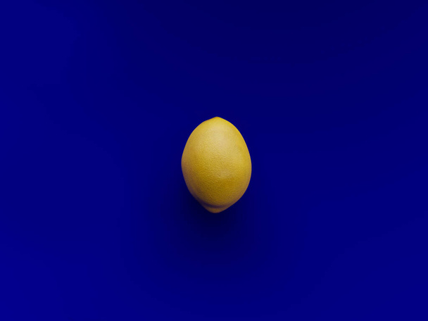 Een gele citroen over een levendige blauwe achtergrond gezien van boven - 3d rendering - Foto, afbeelding