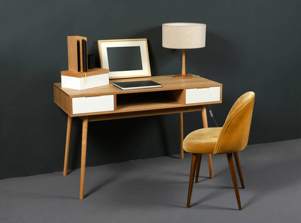 Vieux bureau vintage en bois avec lampe de table rétro, cadre photo et chaise facile dans un intérieur de chambre avec décor gris
 - Photo, image