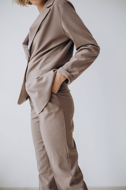 Retrato de una atractiva mujer rubia posa para la publicidad de una tienda de ropa de mujer vestida con un traje con chaqueta y pantalones y zapatos
 - Foto, imagen