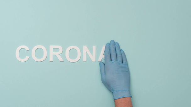 Stop motion animation of doctor covering coronarirus lettering isolated on blue - Πλάνα, βίντεο