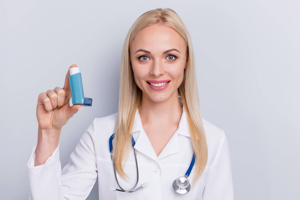 Close-up portrait of her she nice attractive lovely blonde cheerful girl medic specialist stethoscope holding in hand spray bronchitis tracheitis cure remedy isolated on grey pastel color background - Fotografie, Obrázek