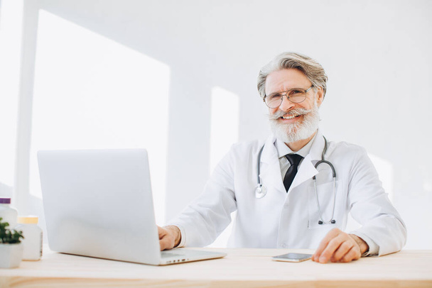 Portrait of senior doctor sitting in medical office - Photo, Image