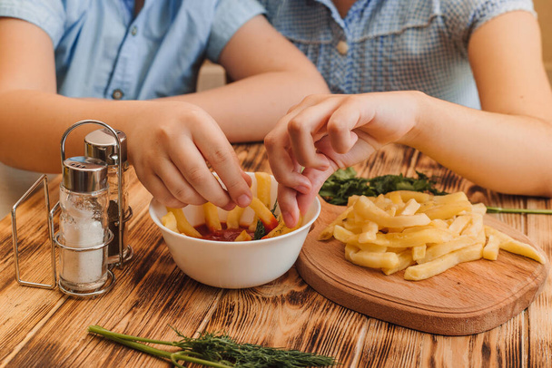 Jongen en meisje genieten van frietjes thuis tijdens quarantaine - Foto, afbeelding