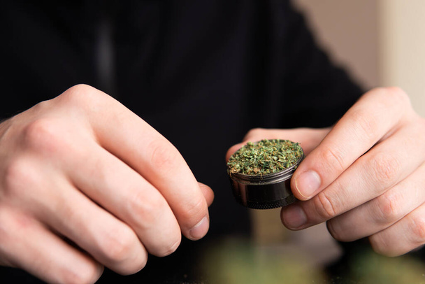 Man rolling a marijuana weed blunt. Close up marijuana joint with lighter. Man rolling marijuana cannabis blunt. - Фото, зображення