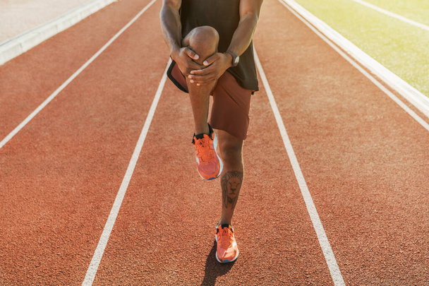 Cropped shot of male athlete stretching on running track at sports stadium - Fotografie, Obrázek