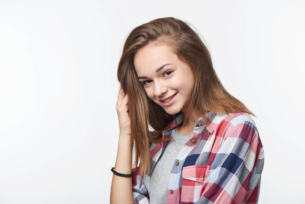 Smiling relaxed teen girl touching her hair looking at camera, studio portrait - Valokuva, kuva