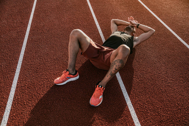 Runner lying on the track resting after workout - Foto, Imagen