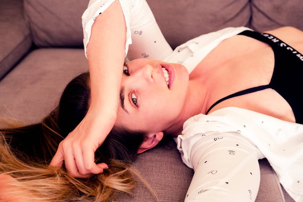 joven hermosa mujer en sujetador y camisa posando en el sofá
 - Foto, Imagen
