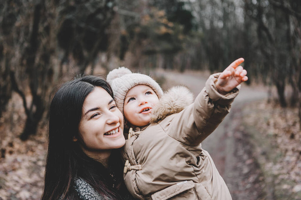 Porträt einer jungen schönen Mutter und ihrer niedlichen kleinen Tochter, die an einem kühlen Herbsttag im Park spazieren geht - Foto, Bild
