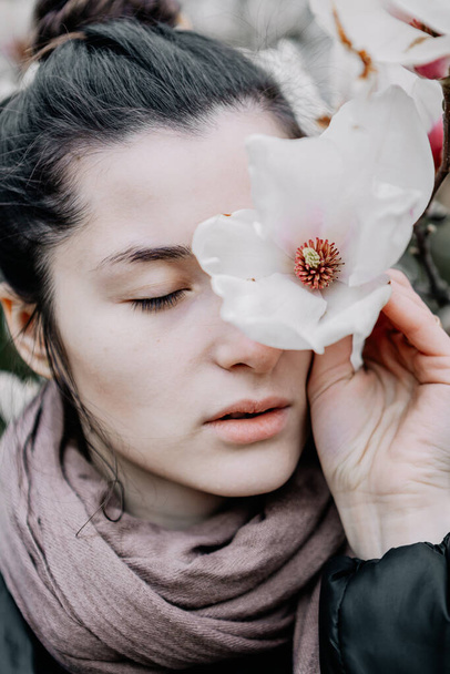 young girl enjoys the flowering of white and pink magnolia flowers at the University of Chernivtsi, Ukraine - 写真・画像