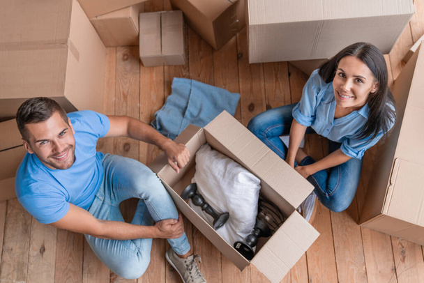Top view of cheerful young couple unpacking boxes in their new apartment - Φωτογραφία, εικόνα