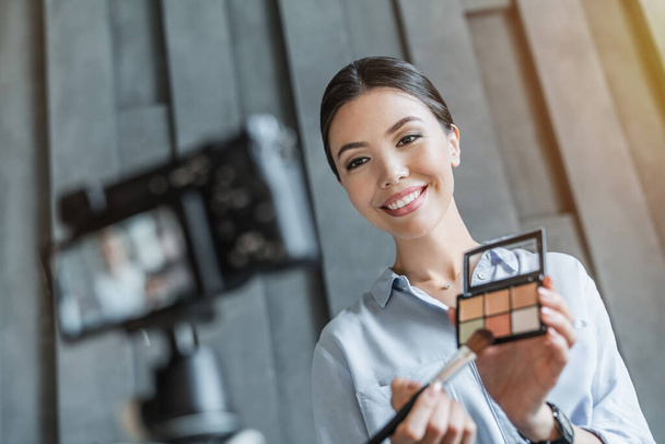 Woman showing makeup palette on camera and recording video for blog - Fotografie, Obrázek