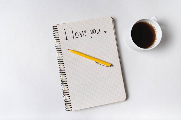 TE AMO escrito en cuaderno sobre fondo blanco. Café de la mañana y mensaje para amado
. - Foto, imagen
