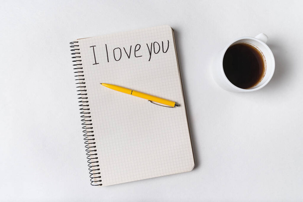 Te amo, escrito en un cuaderno. Café de la mañana y mensaje para ser amado. Fondo blanco
. - Foto, imagen