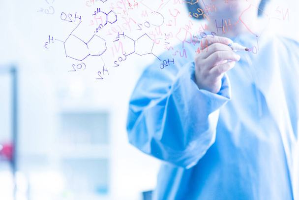 Die Wissenschaftler, Chemiker, entdecken die chemische Formel, die auf Whiteboards geschrieben wird, im Labor. Forscher entdecken Impfstoff oder Medikament für COVID19 infizierte Patienten. - Foto, Bild