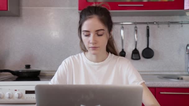The girl works at home on a laptop, hears a phone call and answers it - Záběry, video
