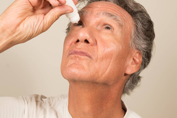 Senior Man Applying Eye Drops to his Eyes - Photo, Image