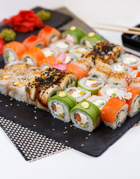 Een paar sushi. Verschillende soorten Maki en Nigiri sushi met gember en wasabi saus. Heldere en kleurrijke service in het restaurant. Geserveerd op donkere stenen sushi planken. Enorme sushi set. - Foto, afbeelding