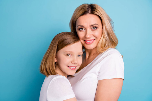 Cloeup profile photo of two people beautiful mommy lady small little daughter blonds hugging good mood best friends wear casual white s-shirts isolated blue color background - Zdjęcie, obraz