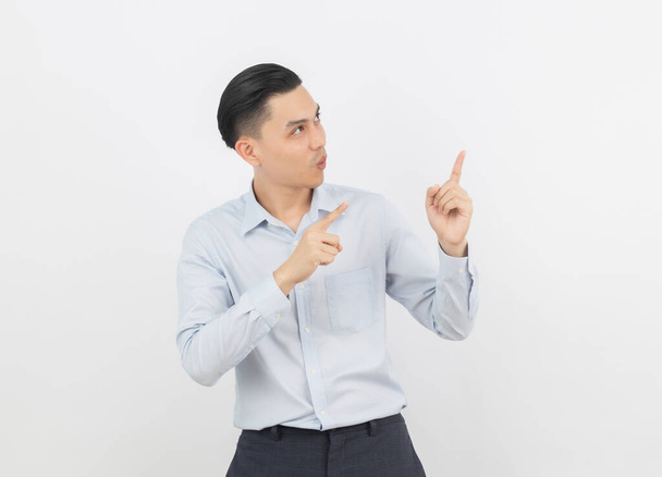 Giovane uomo d'affari asiatico con camicia blu che punta al lato con una mano per presentare un prodotto o un'idea isolata su sfondo bianco. - Foto, immagini