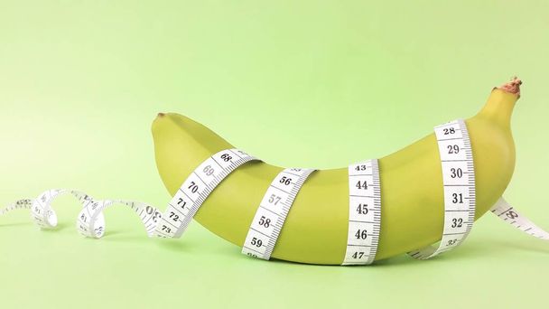 Свіжі зелені фрукти, загорнуті в вимірювальну стрічку. Концепція мети схуднення, мета дієти
 - Фото, зображення