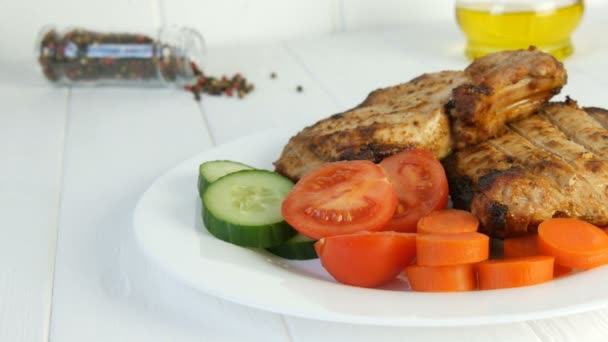 Tasty juicy fresh slices of grilled steak entrecote pork meat next to cherry tomatoes and fresh vegetables cucumbers on a white restaurant plate - Footage, Video