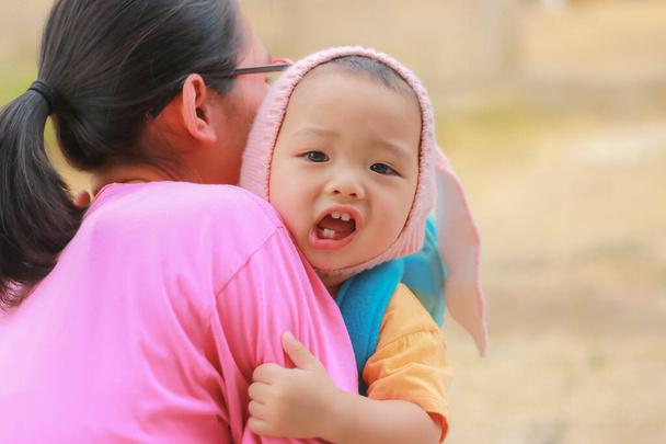 Close-up de mãe asiática ou babá segurando criança agitada. Cuidado do bebê e conceito de infância
. - Foto, Imagem