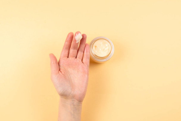 Hand cream and woman hands on a beige background. Copy space.  - Foto, Bild