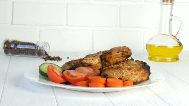 Νόστιμες ζουμερές φρέσκες φέτες ψητής μπριζόλας εντεκότε χοιρινό κρέας δίπλα σε ντοματίνια και φρέσκα λαχανικά αγγούρια σε λευκό πιάτο εστιατορίου - Πλάνα, βίντεο