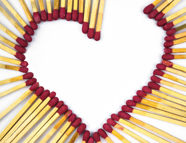 Розбите серце, зроблене з спаленими червоними паличками сірників перед білим ізольованим тлом
 - Фото, зображення