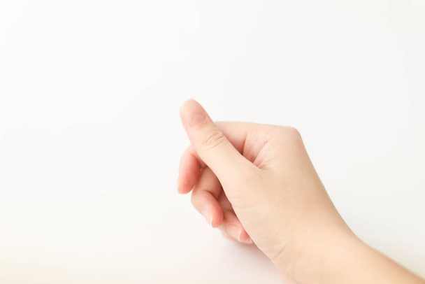 Cerca de la mano de mujer con uñas forma de cuadrado suave sostiene algo en los dedos. La hembra mantiene el objeto virtual. Cuidado de uñas en casa. Copiar espacio
 - Foto, Imagen
