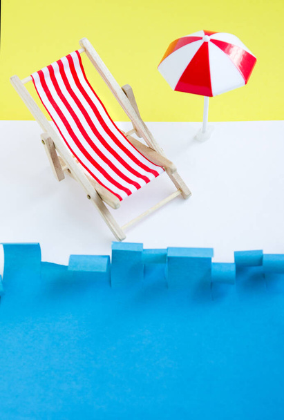 Red deck chair with umbrella near sea. Toy recliner on blue and yellow background. Concept summer rest. Vacations. - Foto, Bild