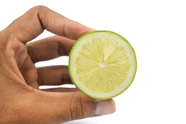 Een persoon die een half gesneden rond en smakelijk citroenfruit zachtjes in zijn hand met zijn vinger - Foto, afbeelding